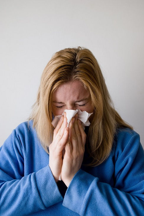 woman with allergies blowing nose