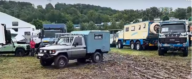 Mehrere Overland Autos stehen auf der aufgeweichten Wiese, bereit zur Abfahrt.
