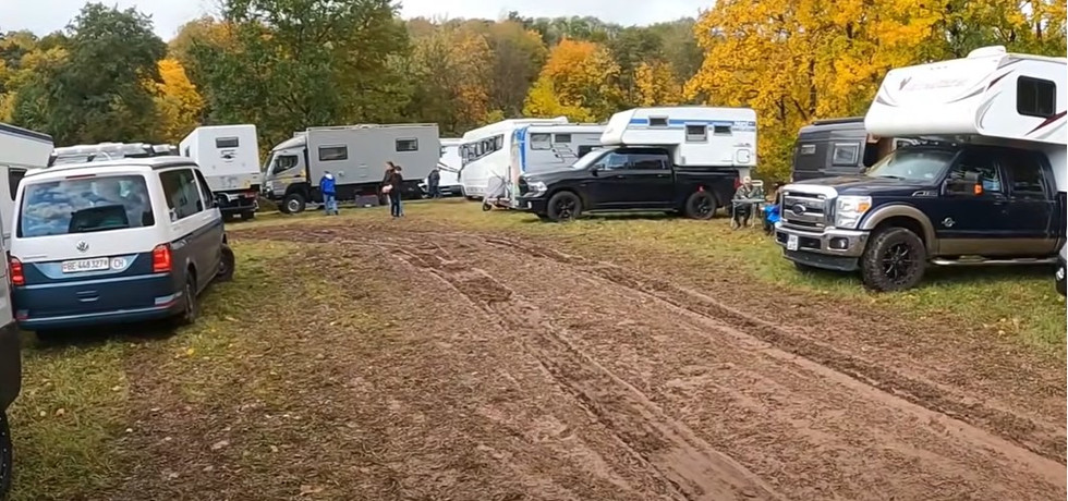 Der Hauptweg ist ausgewaschen und sehr schlecht befahrbar, daneben stehen mehrere Autos noch in Parkposition.