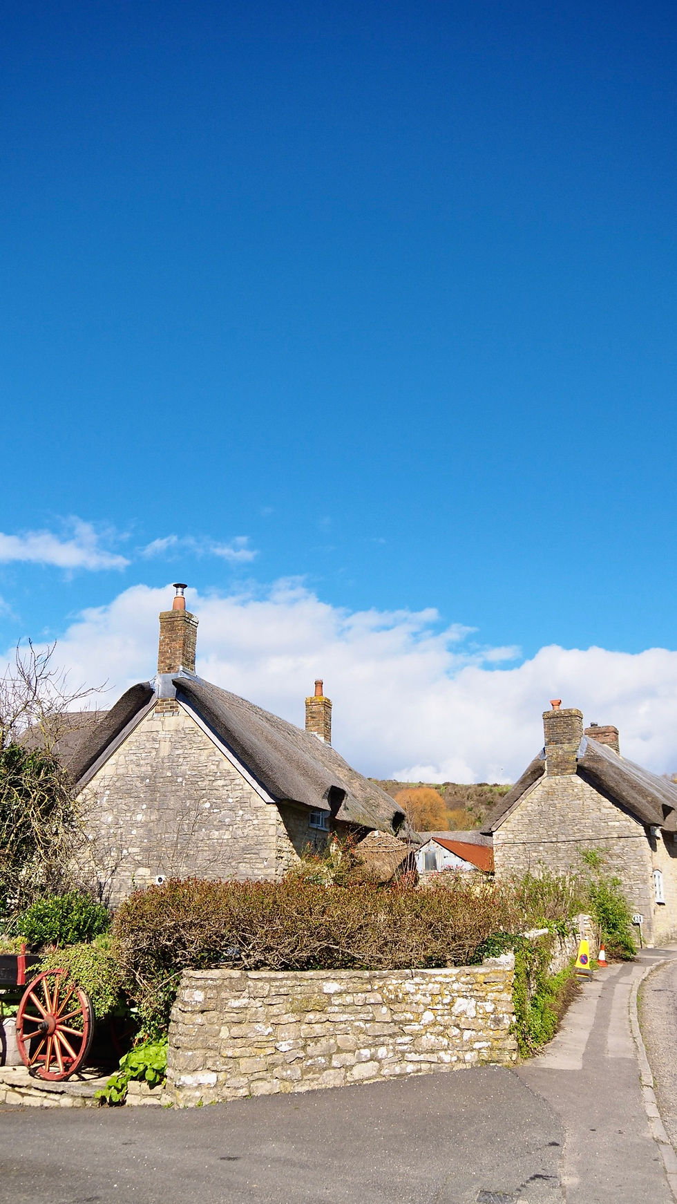 Steinhäuser mit Reet gedeckt, eine Mauer im Vordergrund