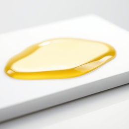 macro image of carrier oil on surface emphasizing viscous texture of oil on solid color wh