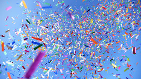 A stock image of rainbow colored confetti against a clear blue sky.