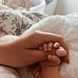 Mother gently holding her baby's hand, symbolizing postpartum bonding, healing, and life after pregnancy