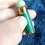 Thumbnail: Fingers holding the Rondo Saville Gun Cartridge Perfume in a Green Case for size comparison