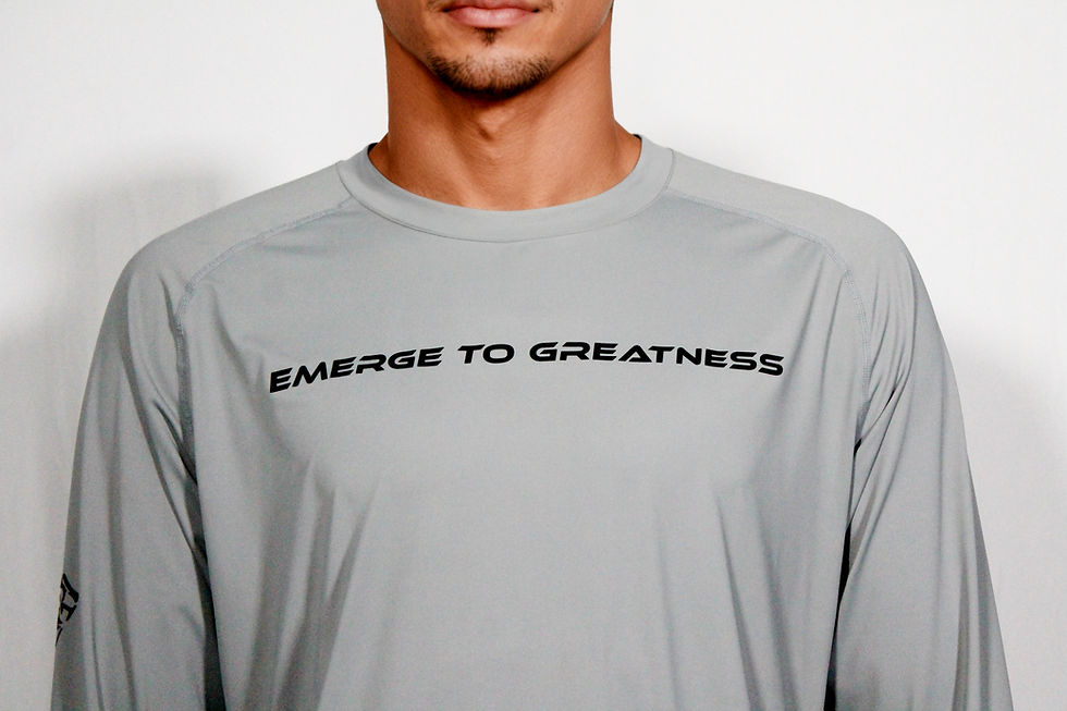 A model wearing a light grey long sleeve dri-fit shirt with "Emerge to Greatness" in black text across the front