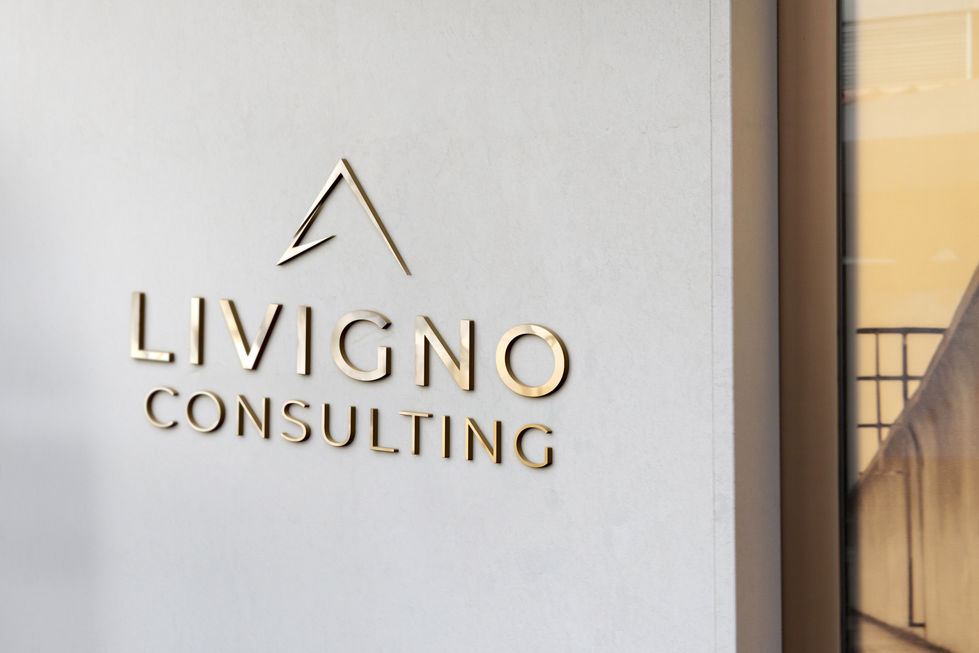 Letreiro dourado da Livigno Consulting aplicado em uma parede de escritório com iluminação lateral.