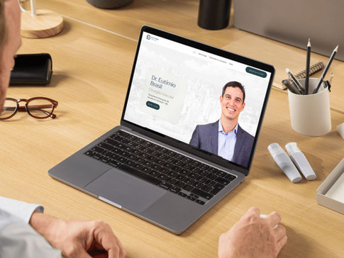 Laptop aberto em uma mesa de escritório mostrando o site profissional do Dr. Eutímio Brasil, com sua foto e título de especialidade.