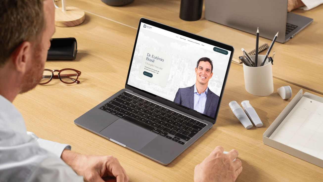 Laptop aberto em uma mesa de escritório mostrando o site profissional do Dr. Eutímio Brasil, com sua foto e título de especialidade.