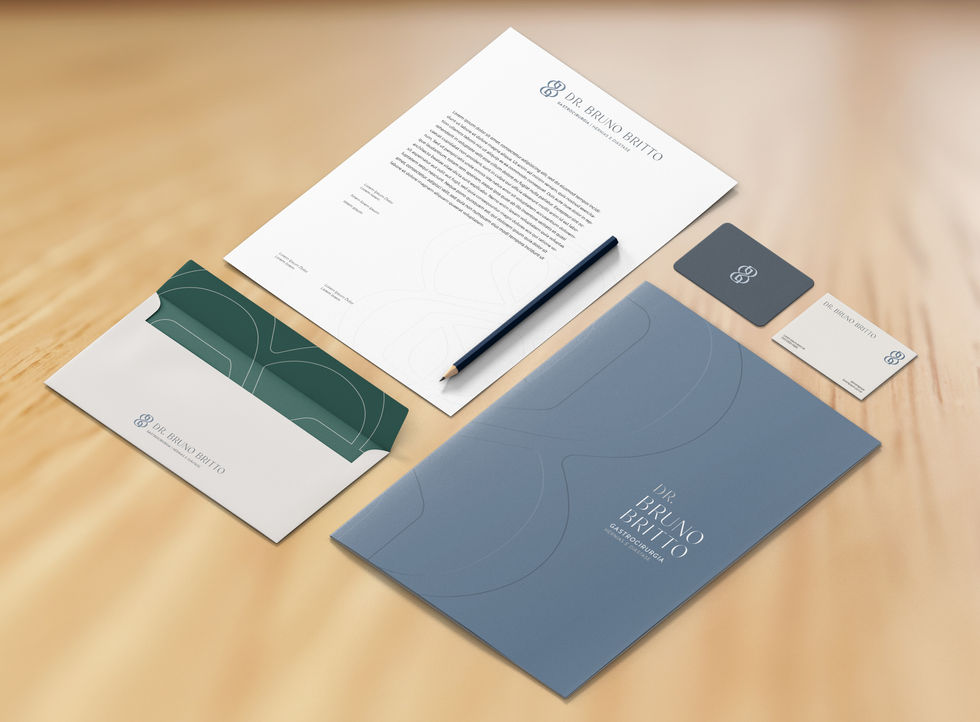 Visão aérea de um conjunto de papelaria institucional organizado sobre uma mesa de madeira. Inclui uma pasta azul-escura, pap