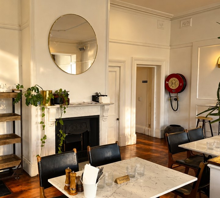 The hearth and the round mirror above it, marble tables in front