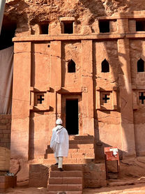 Person betritt Kirche in Lalibela, Äthiopien, rotes Gestein, religiöses Gebäude.