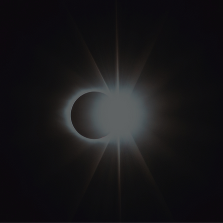 A solar eclipse with one half a dark, outline moon, and the other is the bright, shining sun.