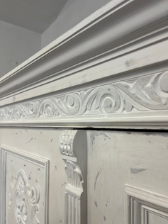 Geschnitzte Verzierungen im Holz eines weißen Kleiderschranks im Shabby Chic Stil