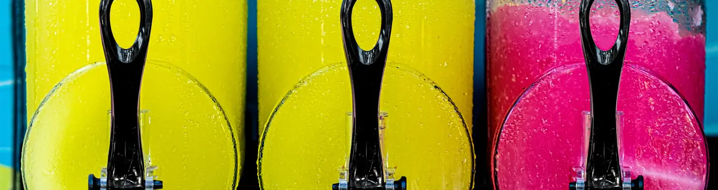 Three vibrant frozen drink dispensers