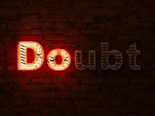 Neon sign reading "Doubt" on a dark brick wall, with red and white glowing letters, creating a moody and thought-provoking atmosphere.