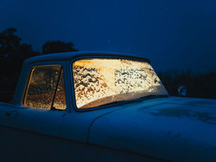 Truck with frosted windows under a dark blue sky, illuminated from within. Snow-covered roof creating a serene, wintry atmosphere.