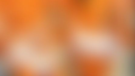 People in orange attire seated, writing on notepads with pencils. Papers and folders on laps, focused atmosphere, indoors setting.