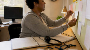 Hands arranging caregiver schedule notes on desk
