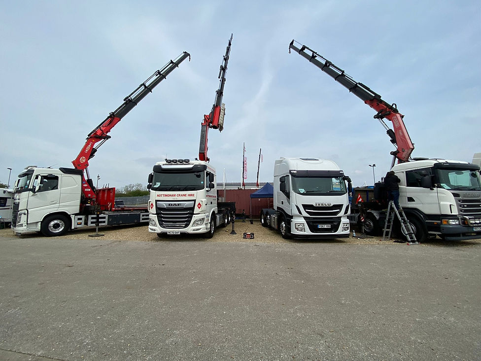 Trucks facing camera in a line, each with a crane on the back