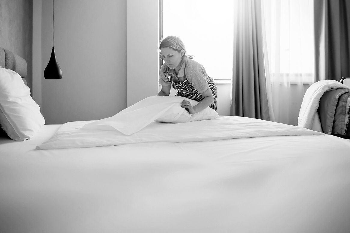 Hotel maid putting on fresh bedding