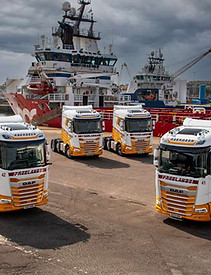 Four Freeland Freight Services Vehicles in front of a boat