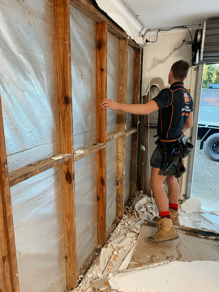 Carpenter repairing termite damage in garage wall