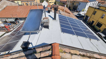 Pannelli solari fotovoltaici e termici su tetto residenziale al sole.