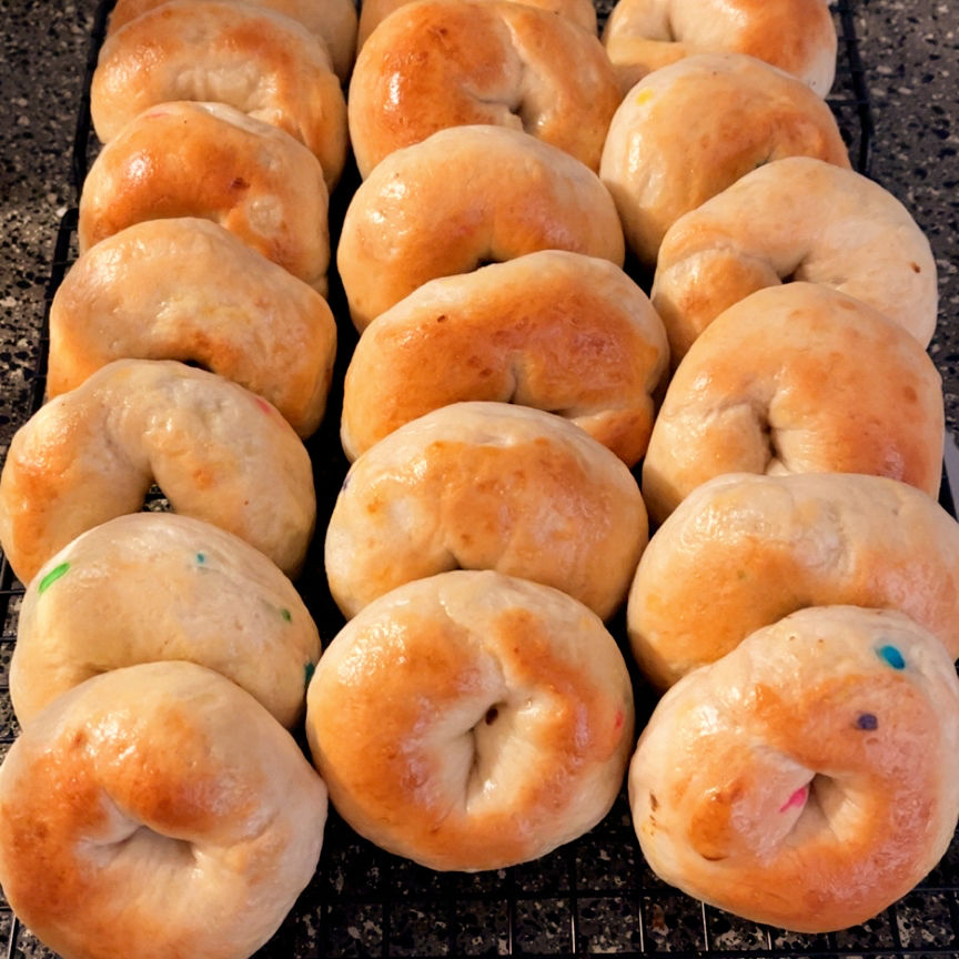 Freshly baked bagels cooling on a black wire rack.