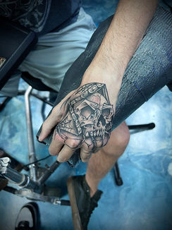 a man has a tattoo of a skull on his hand