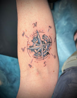 a person has a tattoo of a compass on their arm