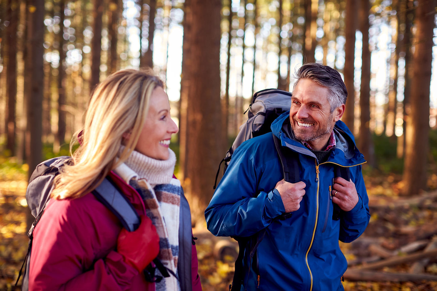 Side View Of Mature Retired Couple With Backpacks Walking Through Fall Or Winter Countrysi