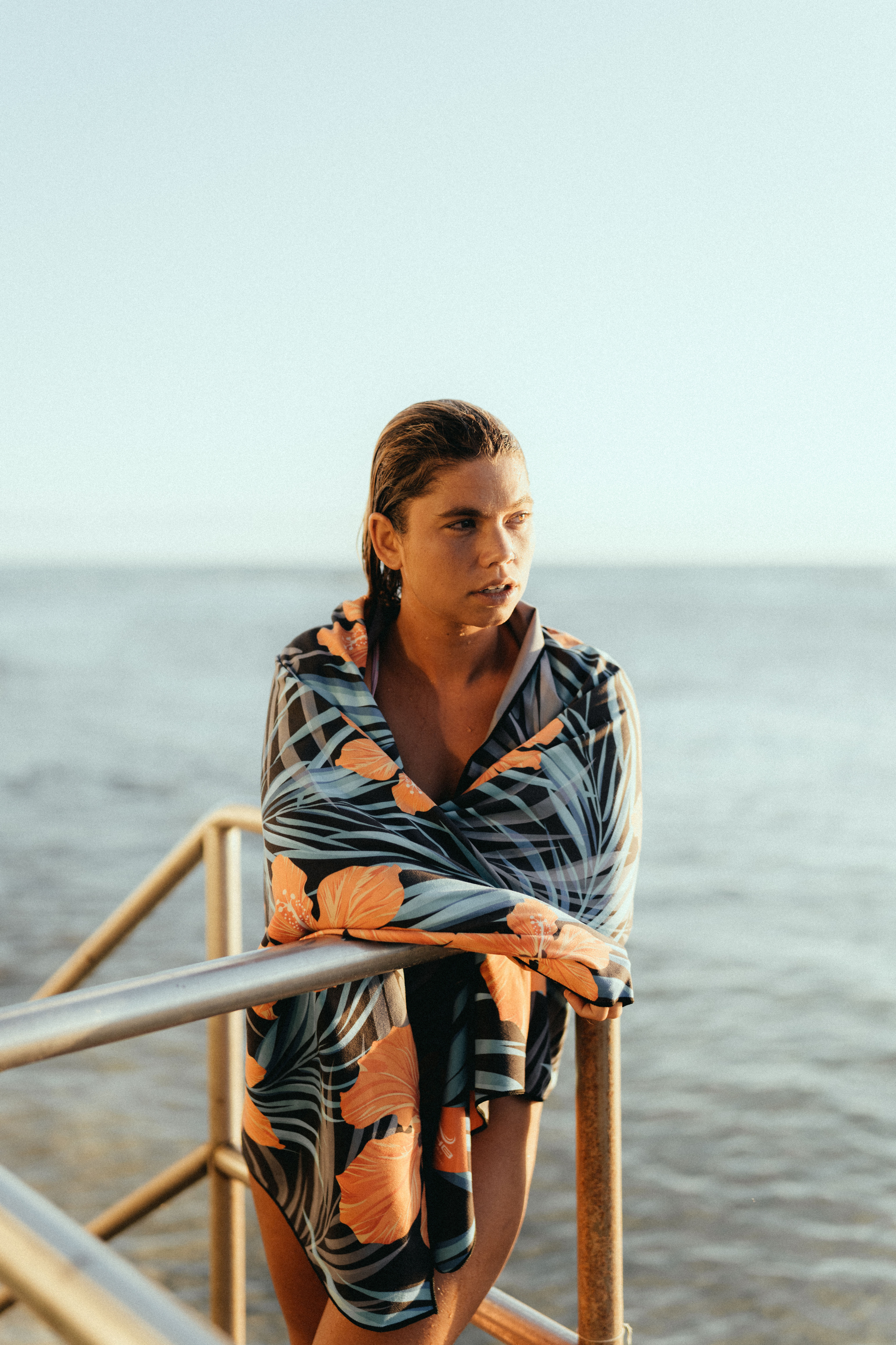 Woman wrapped in the Flower Night beach towel by the ocean.