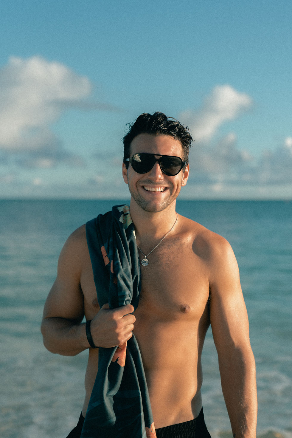 Thumbnail: Man holding a snorkel mask while wearing the Midnight in Honolulu beach towel at the beach.