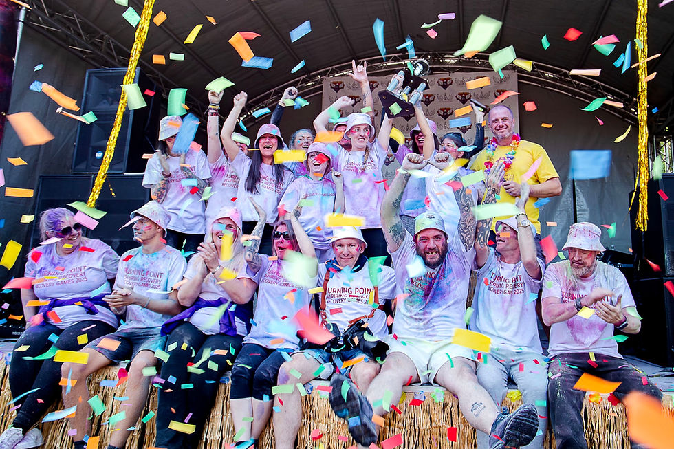 A joyful team celebrates with confetti on stage.