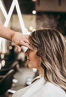 Applying blonde highlights with foils to a client’s long hair in the salon.