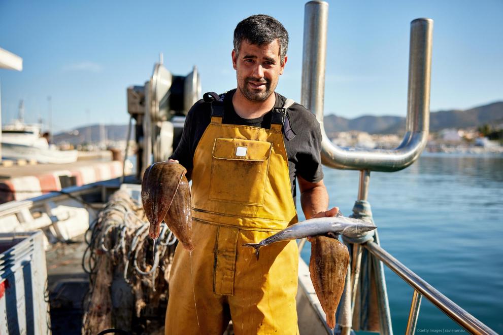 Pescatore con un pesce tra le mani: immagine della Commissione europea sulla visione per pesca e acquacoltura.