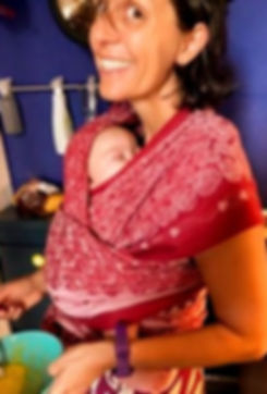 una donna che cucina con un bambino in fascia - sostegno alla genitorialità - doula - massaggio aimi - massaggio misp - bambini