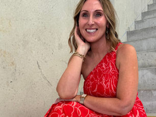 Image of Belinda from Department of Style sitting on concrete steps in a floral red dress perfect for Christmas Celbrations