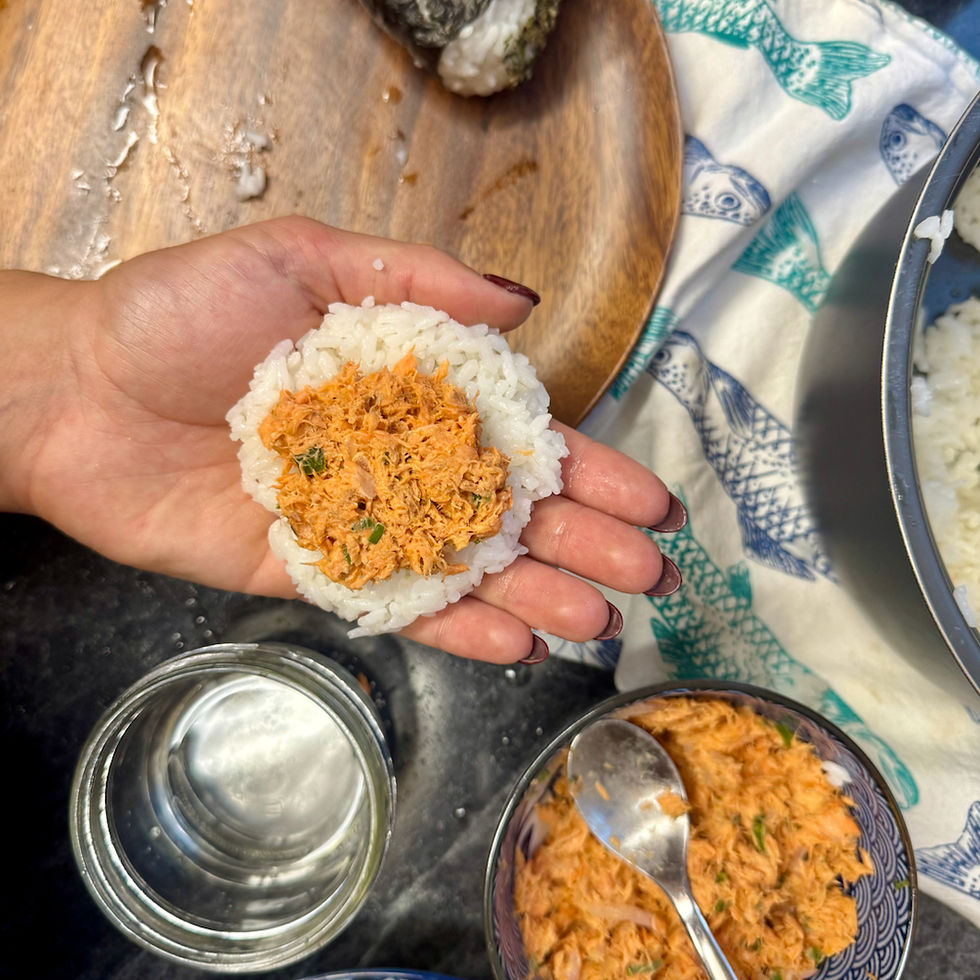 Salmon and rice ball on open palm over fish printed towel