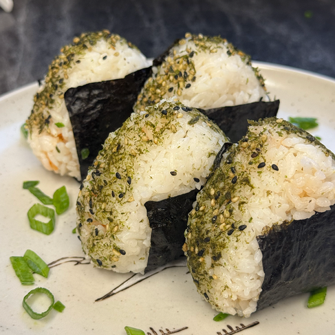 4 finished salmon onigiri rice balls on a plate with green onion