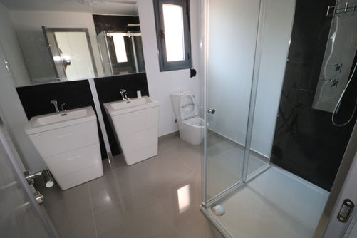 Modern bathroom with double sinks, toilet and shower