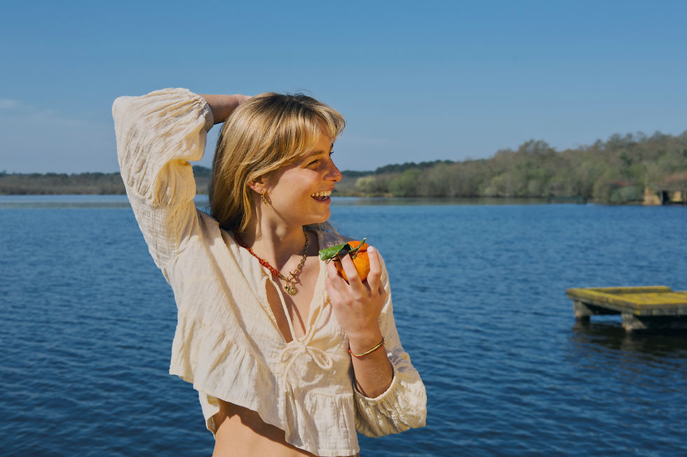 Collier fait main orange porté par une modèle devant le lac d'azur dans les landes