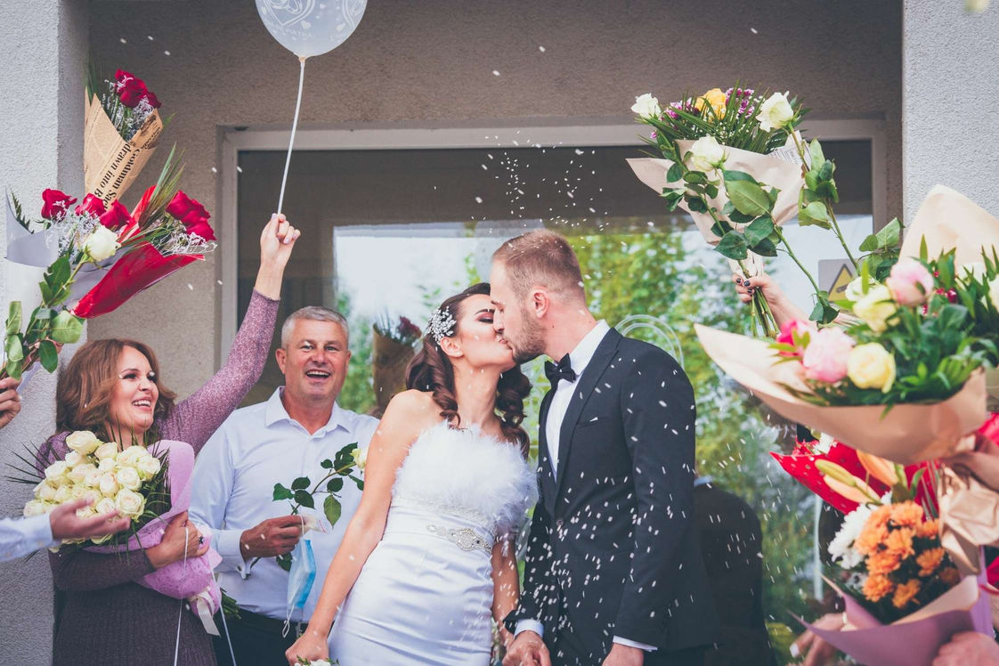 Cuplu sărutat printre flori și confetti după cununia civilă