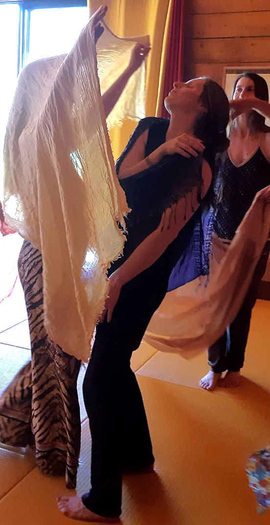 Femmes en mouvement avec des voiles dans un atelier de danse libre guidée.