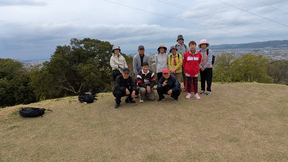 大日山頂上でのハイキンググループの集合写真。青空の下、仲間たちと登山の達成感を共に喜ぶ。