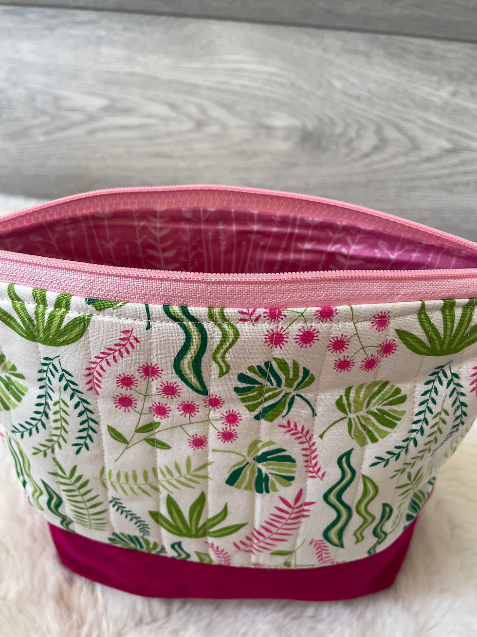 Thumbnail: Green foliage print cosmetic bag with a zip closure and wine-red base.
