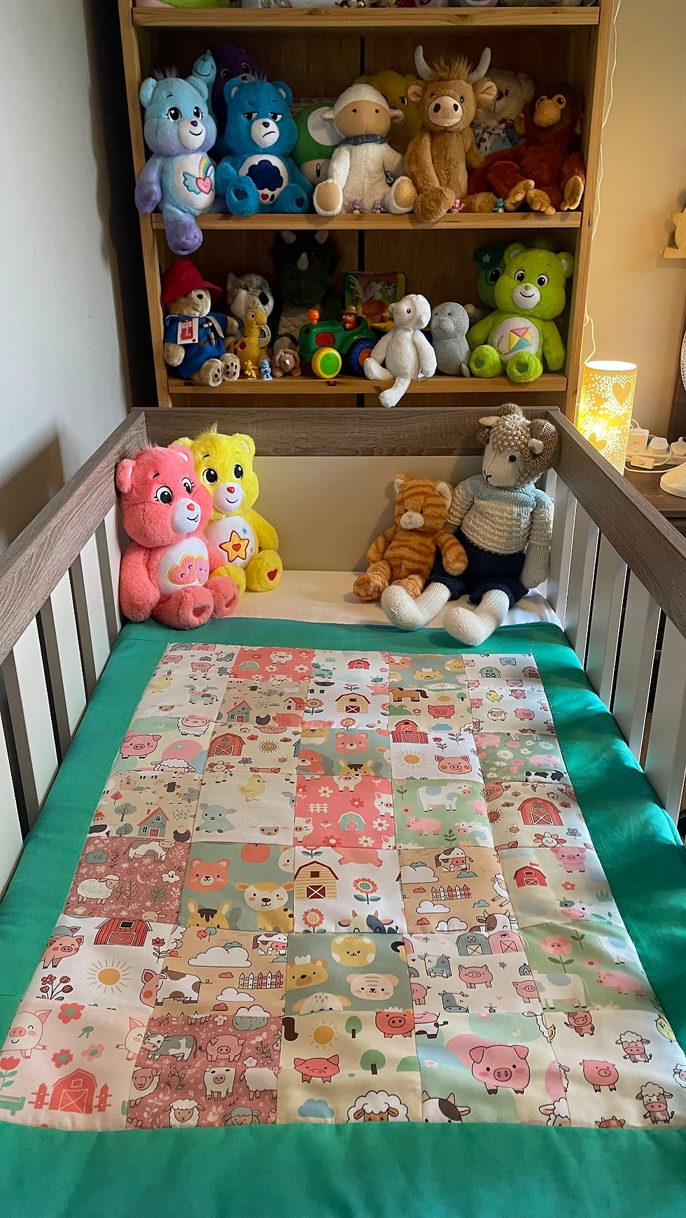 Thumbnail: Handmade farm patchwork baby blanket in a cot in a cosy nursery setting.