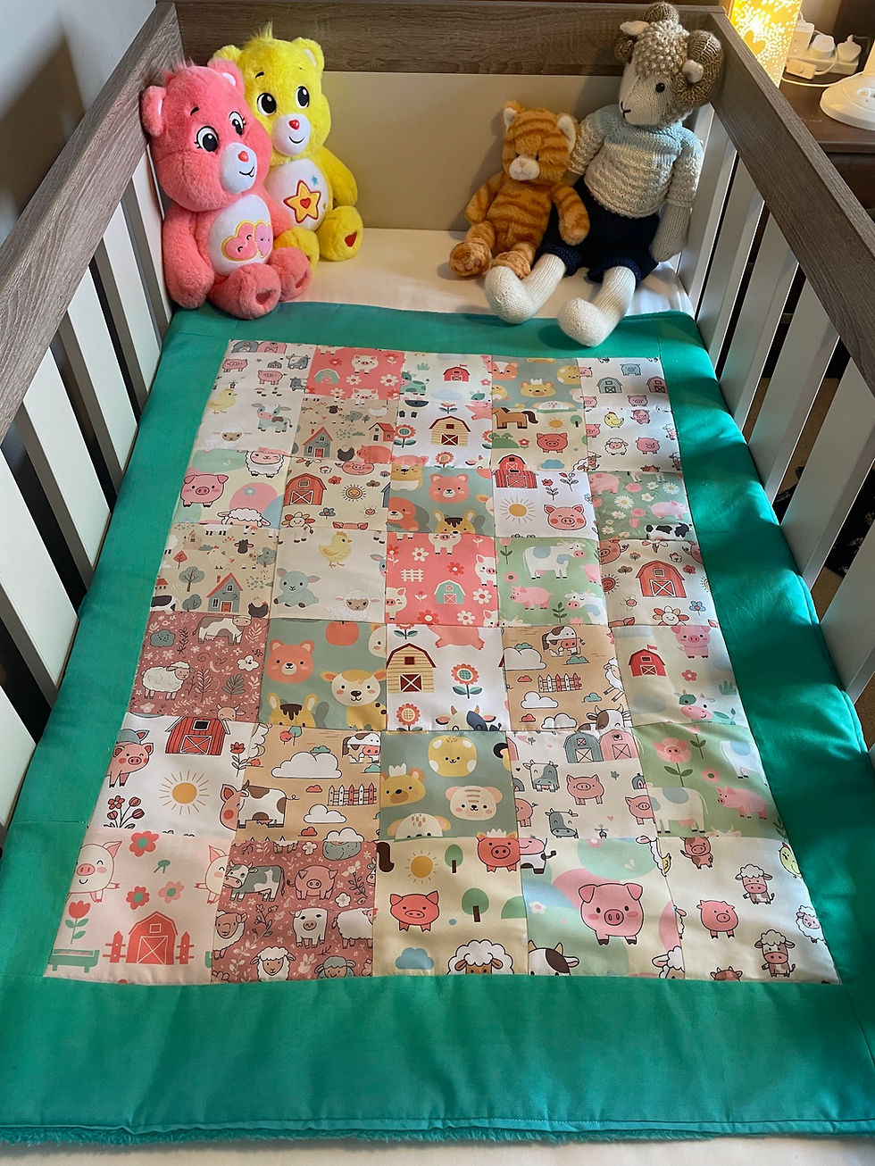 Thumbnail: Farm patchwork baby blanket laid in a cot, styled with plush toys.
