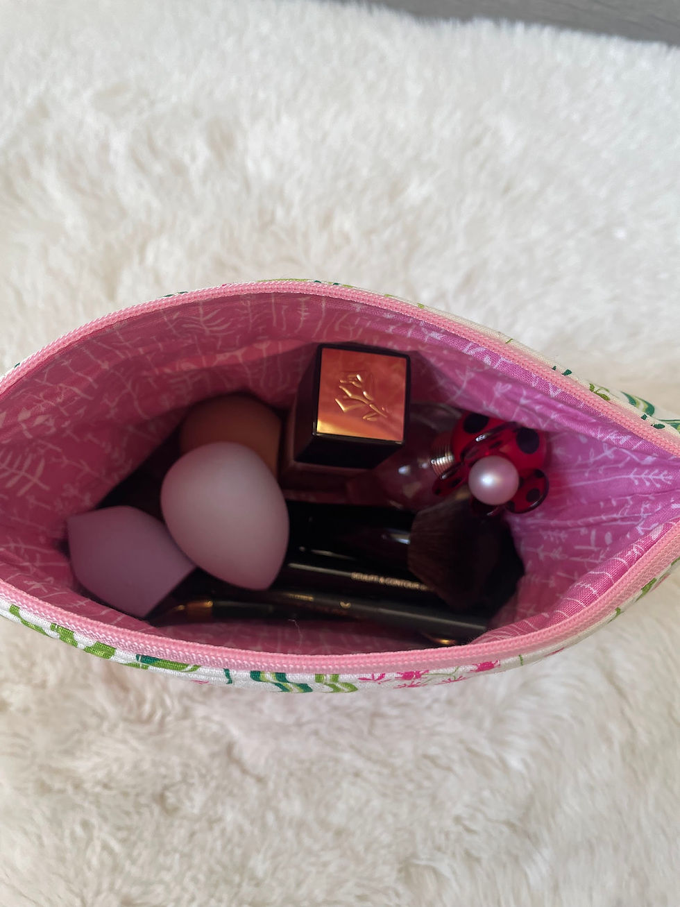 Thumbnail: Tropical-print makeup bag unzipped to show the pink lining and contents.