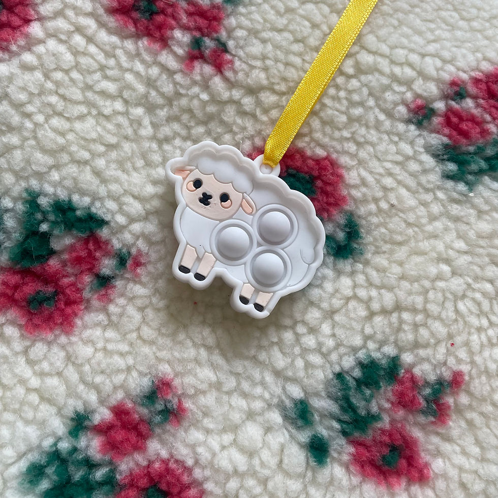 Thumbnail: Sheep popper charm on yellow ribbon, floral fabric background.
